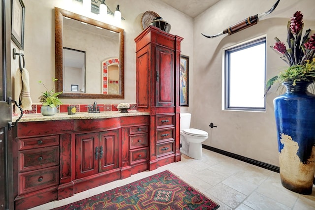bathroom featuring toilet, vanity, and baseboards