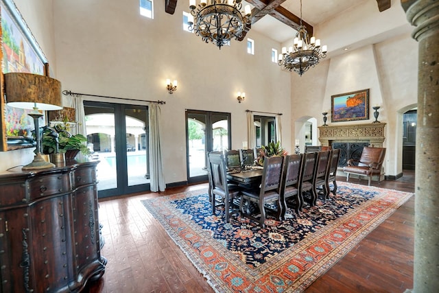 dining space featuring french doors, a towering ceiling, arched walkways, a chandelier, and healthy amount of natural light