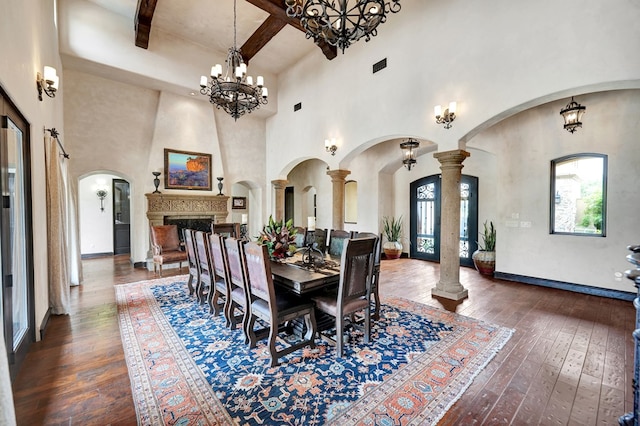 dining area with arched walkways, wood-type flooring, beamed ceiling, a towering ceiling, and a chandelier