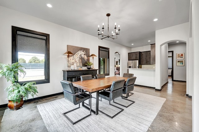 dining space featuring arched walkways, baseboards, concrete floors, recessed lighting, and a chandelier