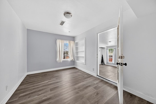2502 W Cuthbert Ave, Midland, TX 79701 - spare room featuring built in features, dark wood-type flooring, and a textured ceiling