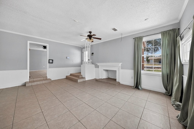 2502 W Cuthbert Ave, Midland, TX 79701 - unfurnished living room with a ceiling fan, a textured ceiling, crown molding, a wainscoted wall, and light tile patterned floors