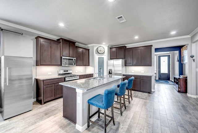 806 Revere Pl, Midland, TX 79706 - kitchen with visible vents, ornamental molding, a sink, light wood finished floors, and stainless steel appliances