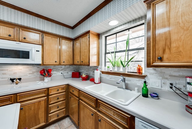 kitchen with sink, a textured ceiling, light tile patterned floors, ornamental molding, and white appliances