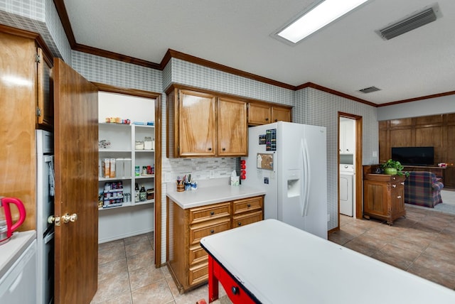 kitchen with light tile patterned floors, crown molding, white refrigerator with ice dispenser, a textured ceiling, and washer / dryer