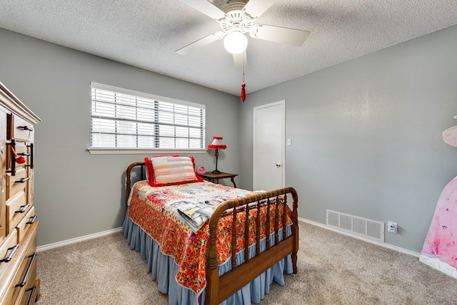 bedroom with ceiling fan, carpet floors, and a textured ceiling