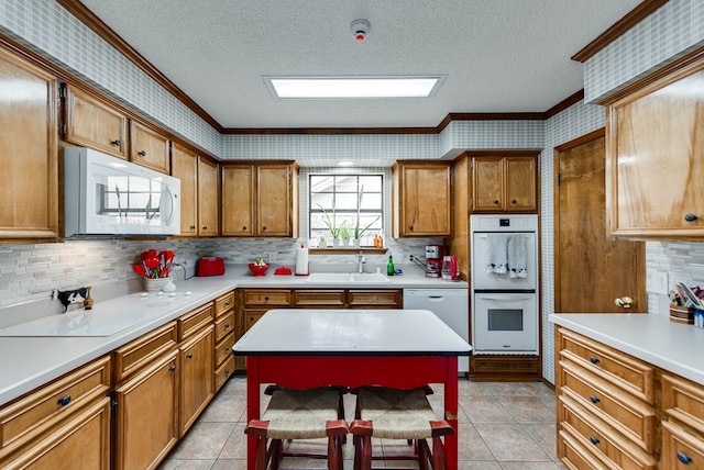 kitchen with white appliances, ornamental molding, a kitchen breakfast bar, and sink