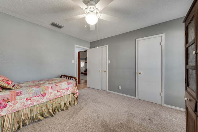 bedroom with ceiling fan, light carpet, and a textured ceiling