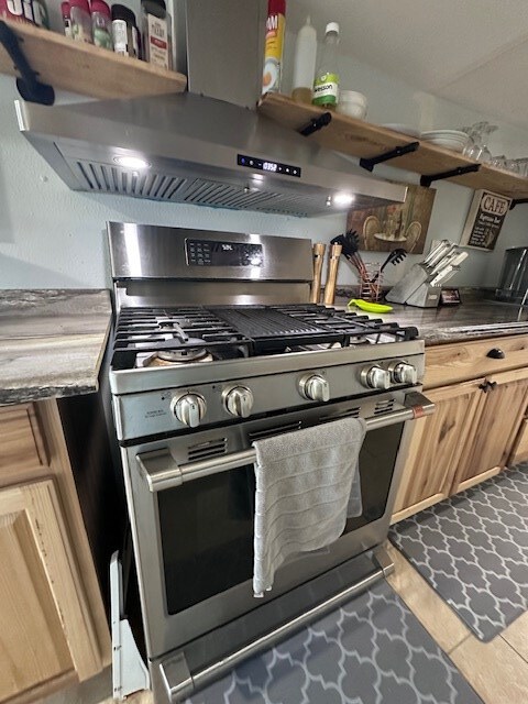 kitchen with light tile patterned floors and stainless steel gas range