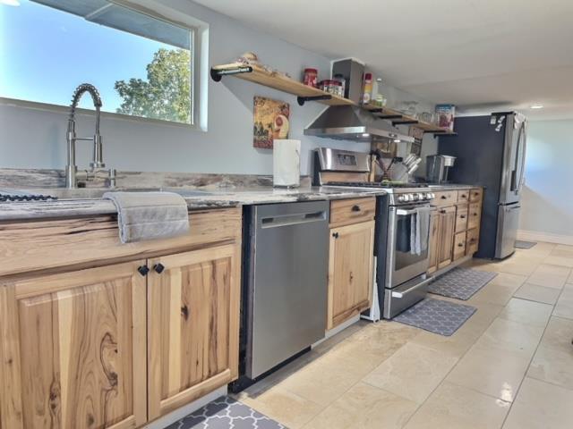 kitchen featuring light brown cabinets, stainless steel appliances, extractor fan, and light tile patterned flooring