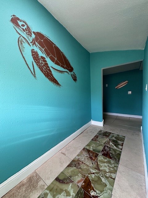 hall with a textured ceiling and lofted ceiling