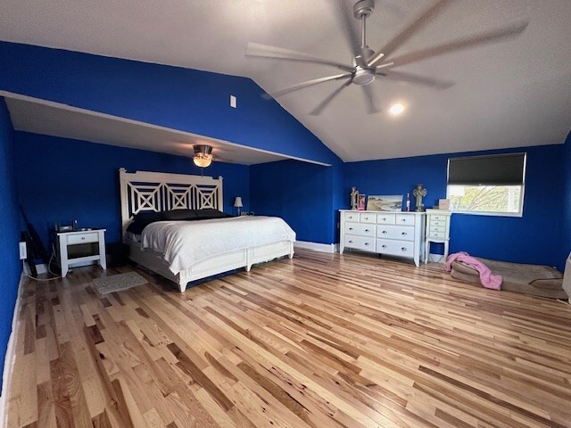 bedroom with ceiling fan, wood-type flooring, and vaulted ceiling