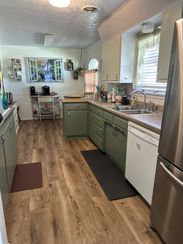 kitchen featuring stainless steel fridge, a textured ceiling, white dishwasher, green cabinetry, and light hardwood / wood-style floors