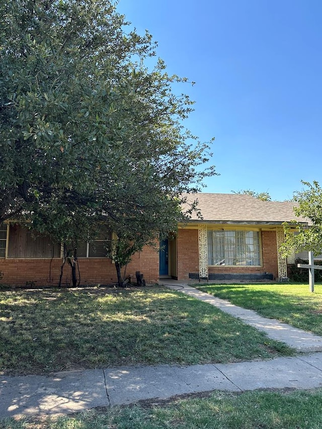 view of front of house with brick siding, a front yard, and fence