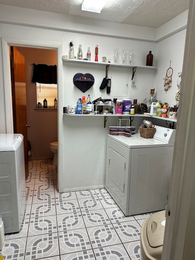 clothes washing area featuring light tile patterned flooring, washer and dryer, and a textured ceiling