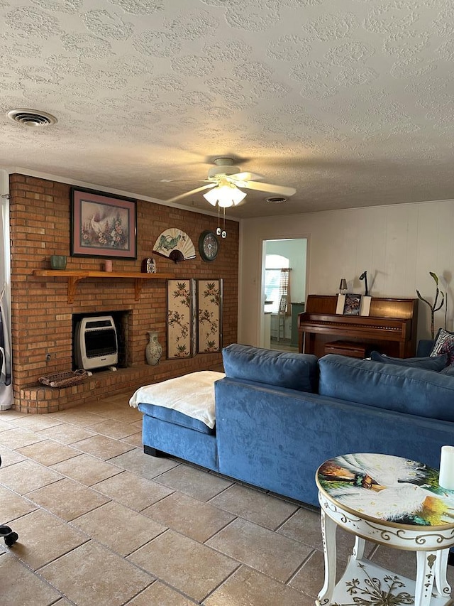 living room featuring a ceiling fan, visible vents, and a textured ceiling