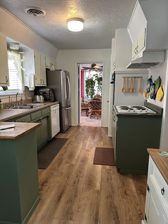 kitchen featuring wood finished floors, white appliances, a textured ceiling, wood counters, and a sink