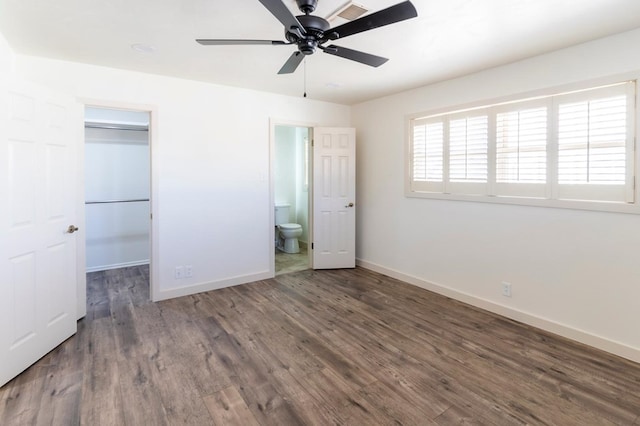 unfurnished bedroom with wood finished floors, visible vents, baseboards, a closet, and a walk in closet