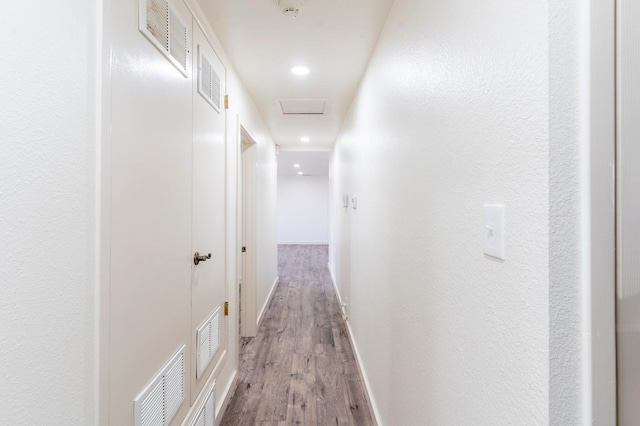 hall with baseboards, visible vents, and light wood finished floors