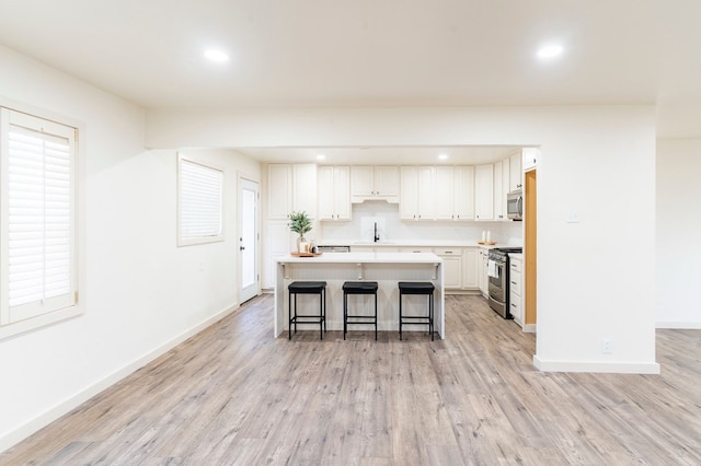 kitchen featuring appliances with stainless steel finishes, light wood-type flooring, white cabinetry, and a kitchen island