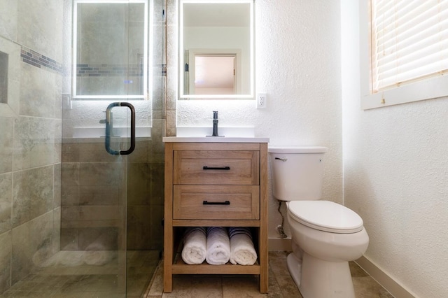 full bathroom featuring a stall shower, baseboards, a textured wall, toilet, and vanity