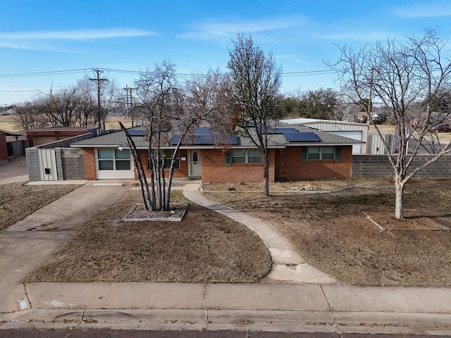 ranch-style home with fence, solar panels, and brick siding