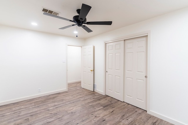 unfurnished bedroom featuring baseboards, a closet, visible vents, and light wood-style floors