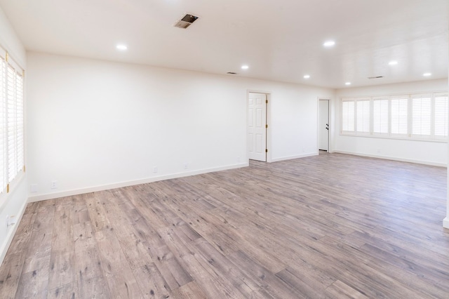 spare room with recessed lighting, visible vents, baseboards, and wood finished floors