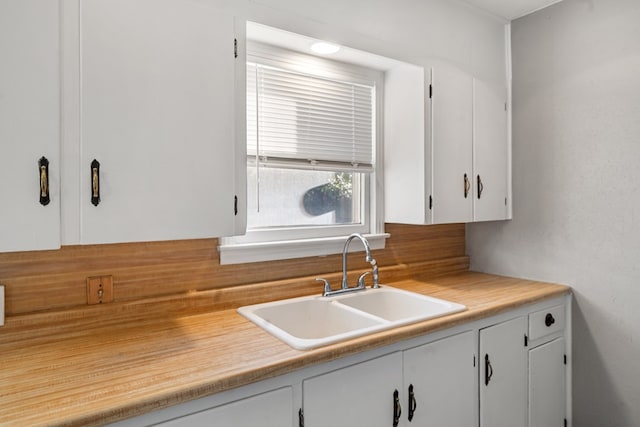 kitchen featuring light countertops, a sink, and white cabinets