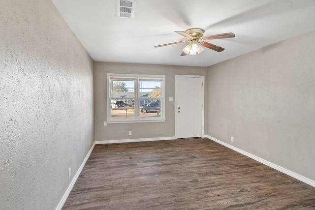 empty room with baseboards, visible vents, and dark wood-type flooring