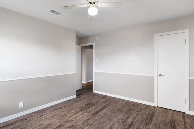 spare room featuring baseboards, dark wood finished floors, visible vents, and a ceiling fan