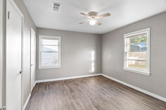 unfurnished room featuring baseboards, visible vents, ceiling fan, and wood finished floors