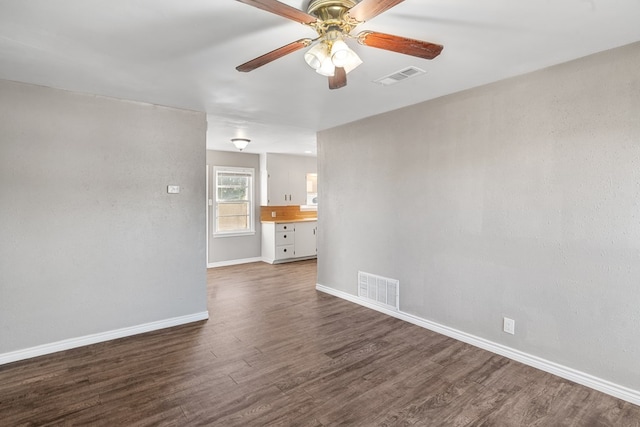 unfurnished room featuring ceiling fan, dark wood finished floors, visible vents, and baseboards