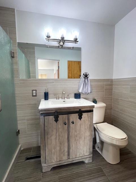 bathroom with vanity, toilet, an enclosed shower, and tile walls