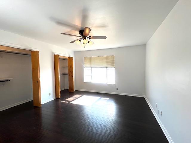 unfurnished bedroom with ceiling fan, dark wood-type flooring, and a closet