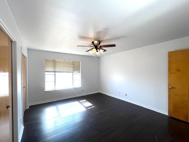 empty room with dark hardwood / wood-style floors and ceiling fan