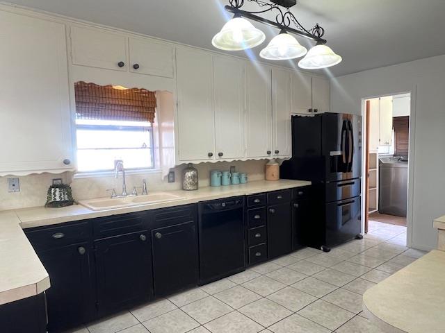 kitchen with black appliances, sink, decorative light fixtures, washer / clothes dryer, and white cabinetry