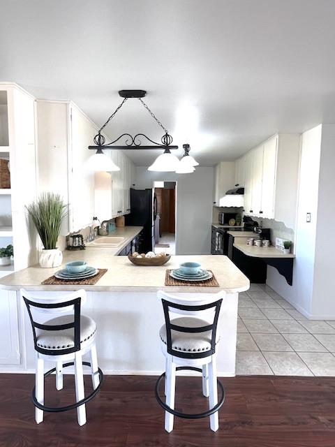 kitchen featuring white cabinetry, black refrigerator, and kitchen peninsula