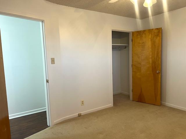 unfurnished bedroom featuring ceiling fan, a closet, carpet, and a textured ceiling