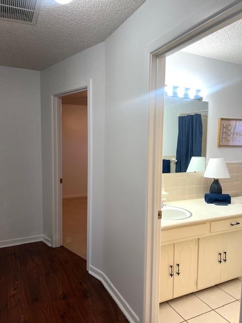 bathroom featuring hardwood / wood-style flooring, vanity, a textured ceiling, and tasteful backsplash