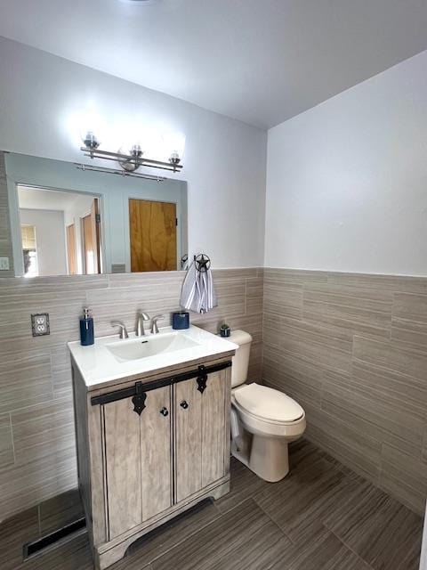 bathroom with vanity, toilet, and tile walls