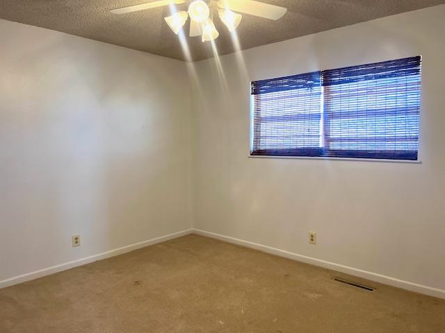 unfurnished room featuring carpet flooring, a textured ceiling, and ceiling fan