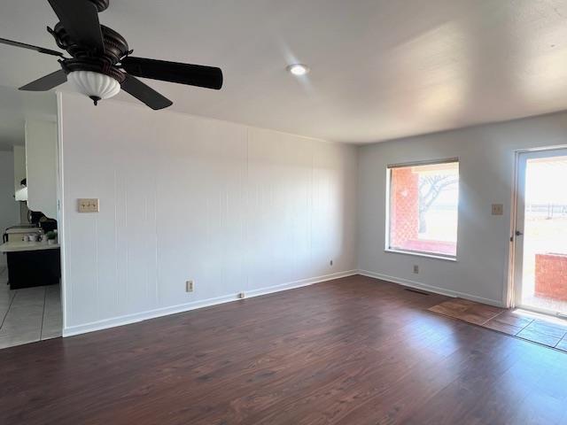 unfurnished living room with ceiling fan and dark wood-type flooring