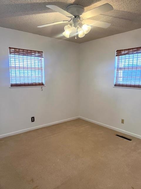 carpeted spare room featuring ceiling fan, a healthy amount of sunlight, and a textured ceiling