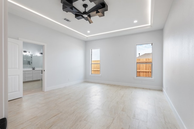 unfurnished room featuring ceiling fan, a tray ceiling, and sink