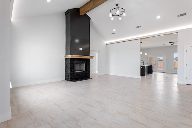 unfurnished living room with sink, beam ceiling, high vaulted ceiling, a notable chandelier, and a fireplace