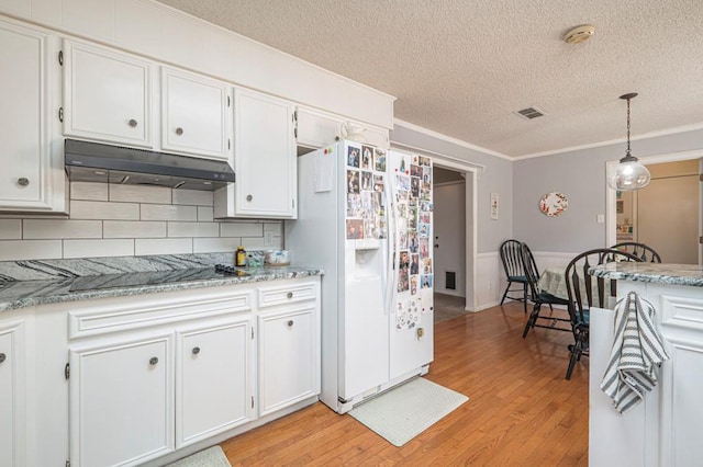 4704 Elma Dr, Midland, TX 79707 - kitchen featuring under cabinet range hood, white fridge with ice dispenser, a textured ceiling, ornamental molding, and light wood-type flooring