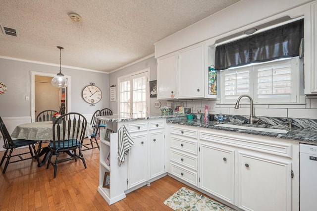 4704 Elma Dr, Midland, TX 79707 - kitchen with dishwasher, a sink, a peninsula, a textured ceiling, and white cabinetry