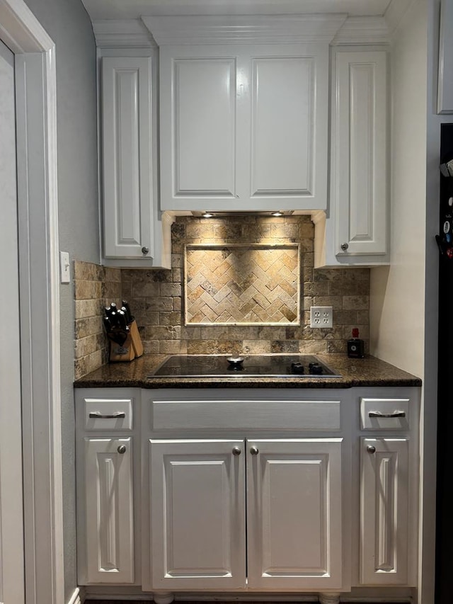 kitchen with white cabinetry, black electric stovetop, decorative backsplash, and dark stone countertops