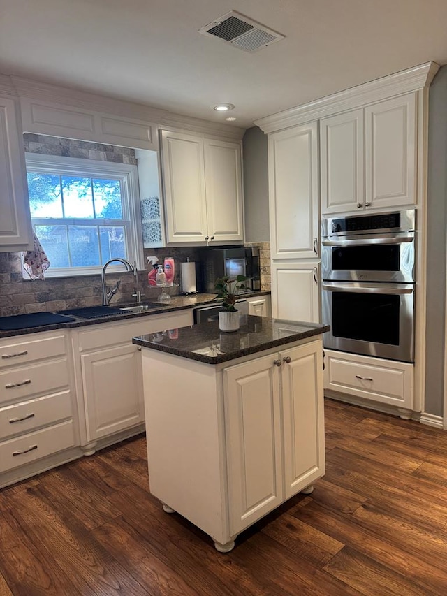 kitchen featuring a center island, sink, white cabinets, and double oven